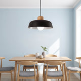 Black dome pendant with a wood top over a dining table in a blue room