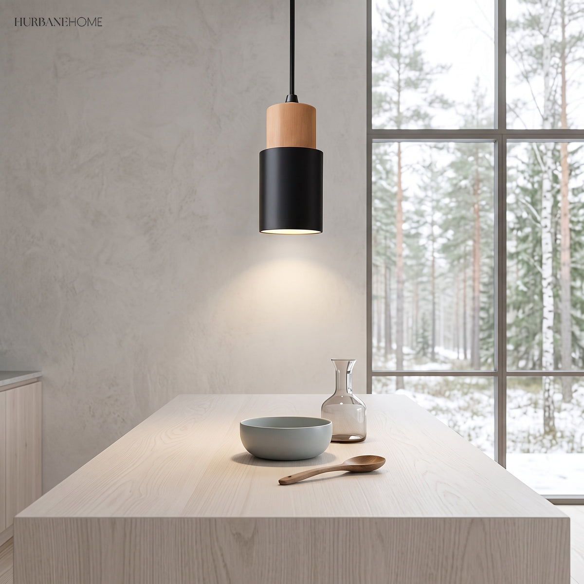 Black cylinder pendant lit above a pale kitchen island by a window