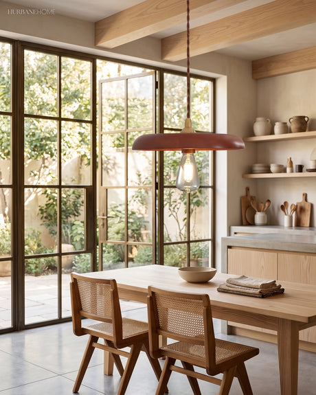 Walnut wood disc pendant lit above a light timber dining table by glass doors