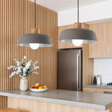 Two grey dome pendants with wood tops above a concrete kitchen island