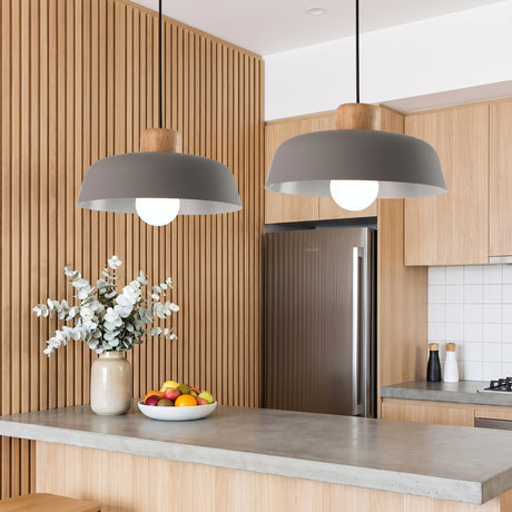 Two grey dome pendants with wood tops above a concrete kitchen island