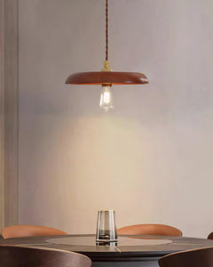 Wood disc pendant lit above a round cafe table with a glass tumbler