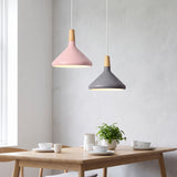 Pink and grey tapered pendants with wood tops over a light oak dining table