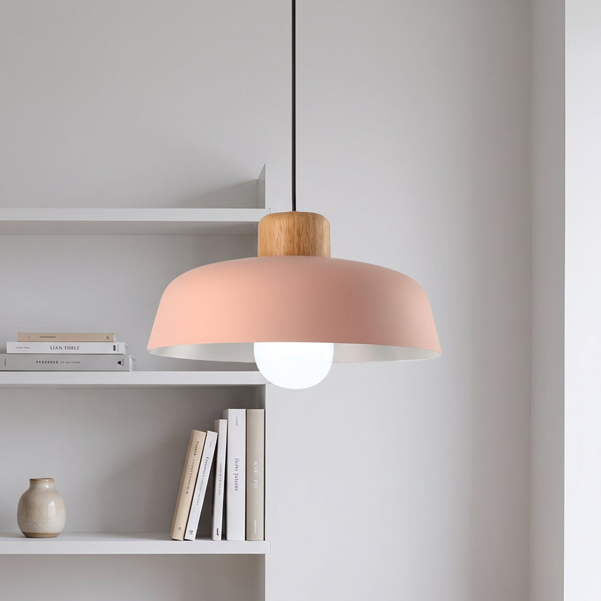 Pink aluminum dome pendant with a wood top hanging beside white shelving