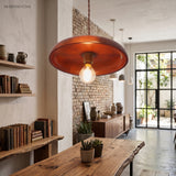 Wood disc pendant with an exposed filament bulb above a rustic kitchen bench