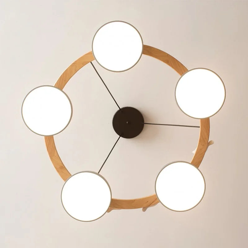 Pastel drum shades and natural wood ring of the round chandelier viewed from below
