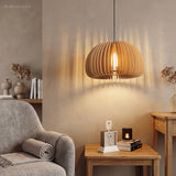 Lit wood slat pendant casting striped light across a plaster wall