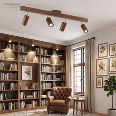 Walnut track light bar lighting a book lined library with a leather armchair