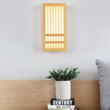 Natural wood wall sconce glowing in a bedroom beside a curtain and nightstand