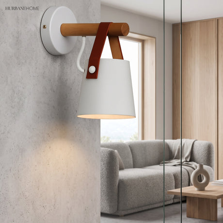 White shade sconce lit on a concrete wall above a grey sofa
