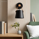 Black wall sconce lit above a timber console and green sofa
