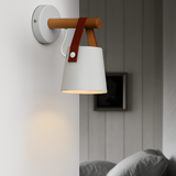White sconce lit on a panelled wall beside a dark alcove