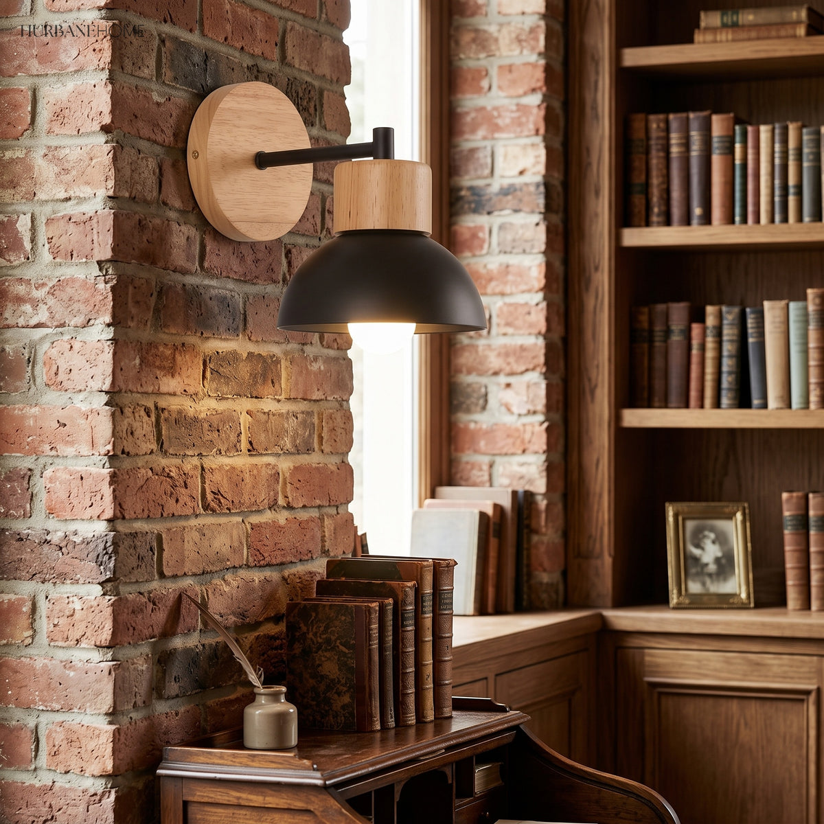 Wood wall sconce with a black dome lit on an exposed brick wall