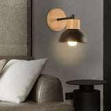Black domed wood sconce lit beside a bed in a grey room