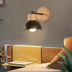 Wood sconce with a black dome lit above a yellow headboard