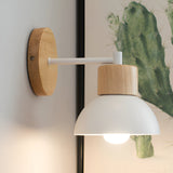 White domed wood sconce lit against a plain pale wall
