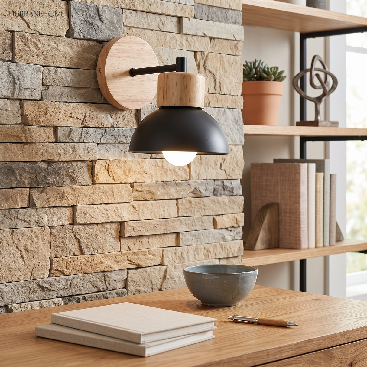 Wood and black iron dome sconce lit above a desk against stone