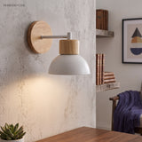 Wood wall sconce with a white dome lit above a desk and shelf