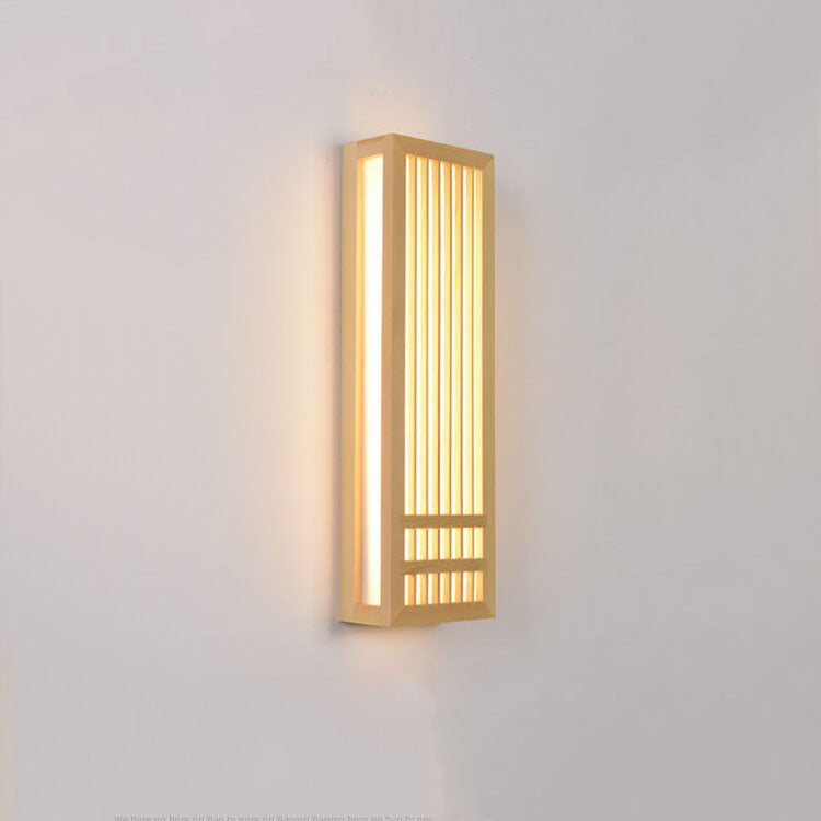 Tall wood wall sconce lit at an angle with warm light on the wall