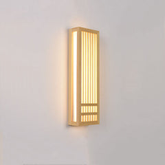 Tall wood wall sconce lit at an angle with warm light on the wall