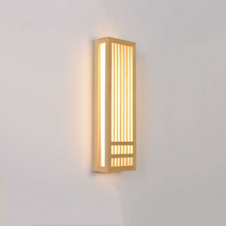 Tall wood wall sconce lit at an angle with warm light on the wall