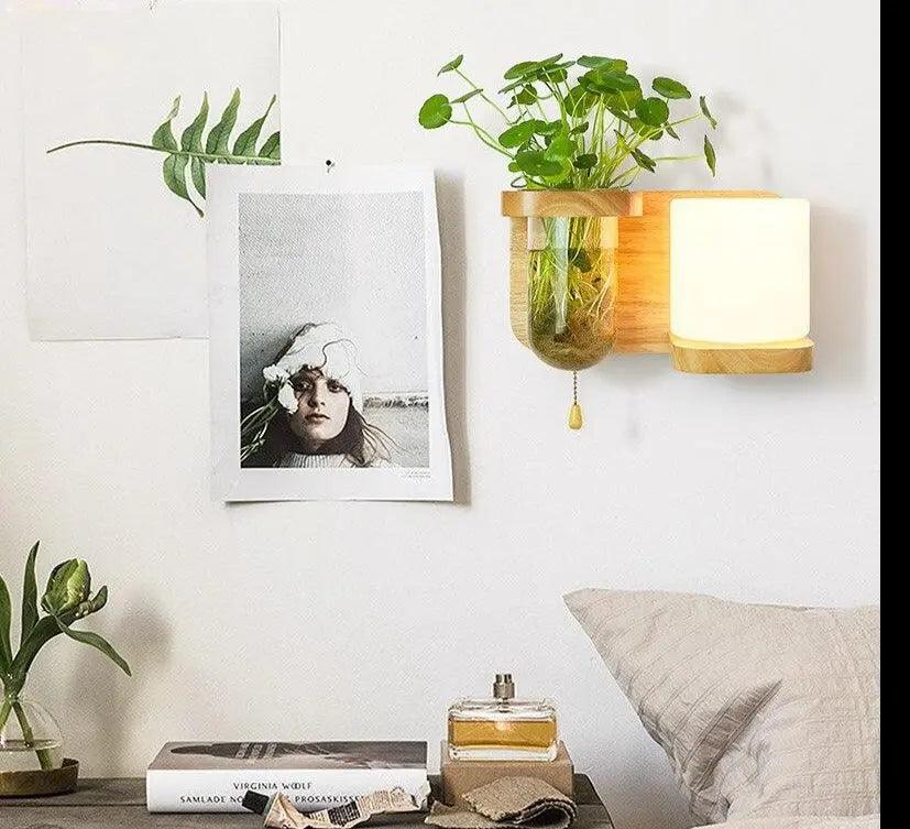 Wood planter sconce with a cylinder shade above a bedside stack