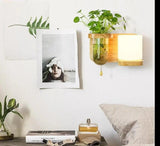 Wood planter sconce with a cylinder shade above a bedside stack