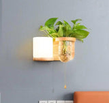 Wood planter sconce lit on a blue grey wall above a sofa