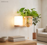 Wood planter sconce lit above a stack of books and a bowl