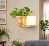 Wood sconce with a cylinder shade and a pull cord beside a plant