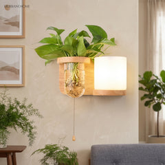Wood sconce with a cylinder shade and a pull cord beside a plant