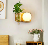 Wood sconce with a glass globe lit beside a propagation vase