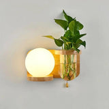 Wood sconce with a warmly lit globe and fresh plant cuttings