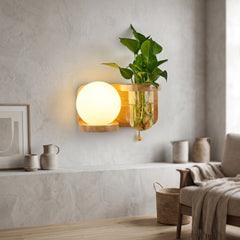 Wood wall sconce with a glass globe and a plant vase beside it