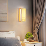 Small and large natural wood wall sconces lit together on a warm wall