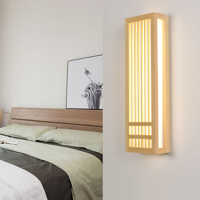Tall lit wood wall sconce on a white wall next to a bedroom scene