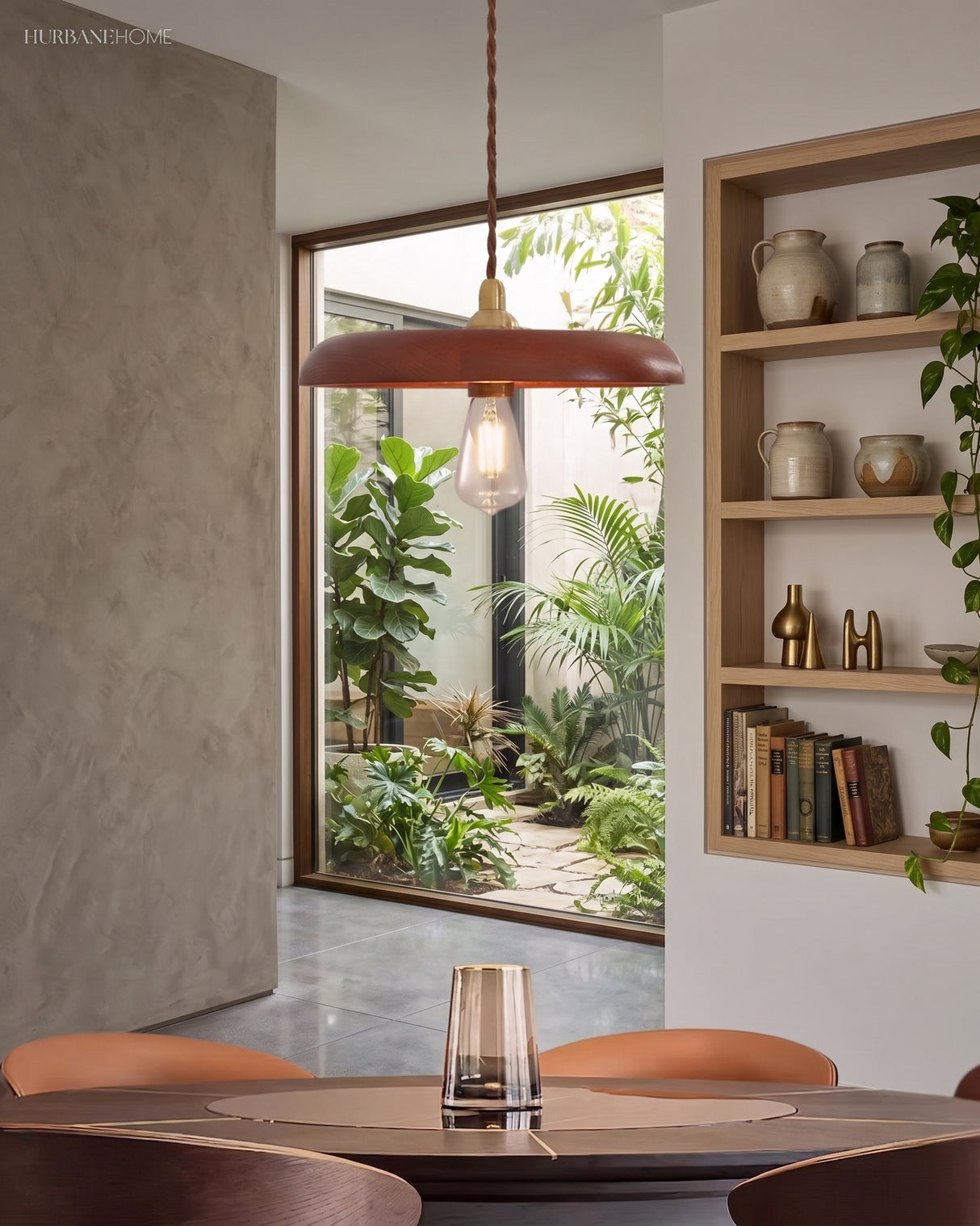 Wood pendant light hanging over a small round table beside a planted courtyard