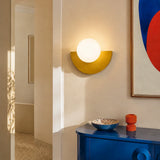 Yellow half moon sconce with the frosted glass globe glowing warmly
