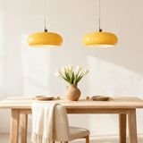 Two yellow glass pendant lights above a wooden dining table with white tulips