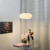 Two yellow glass pendant lights above a round table near a macrame hanging