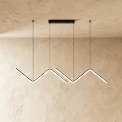 Three black zigzag pendant bars lit in a row against a plaster wall